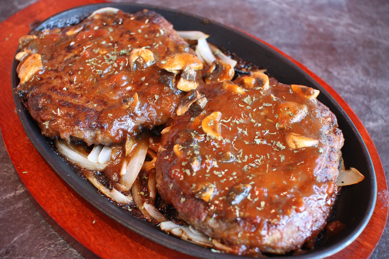 Hamburger Steak sizzling on a cast-iron plate